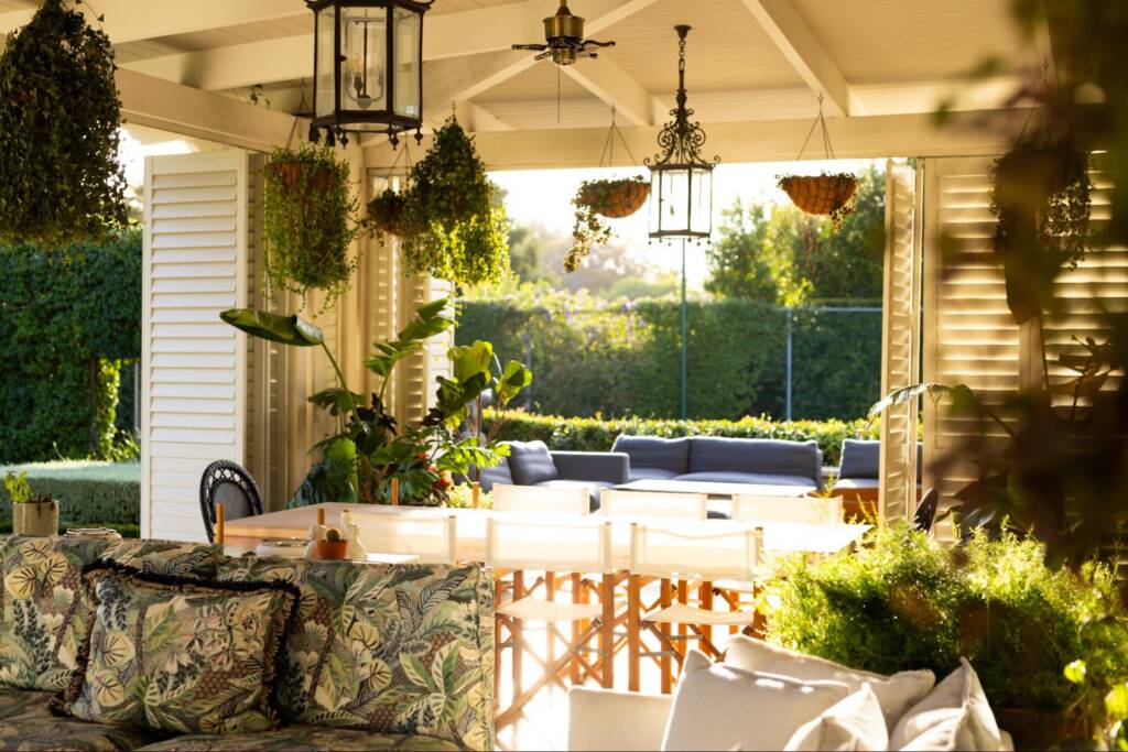 A sunlit patio with lush greenery and cozy seating, creating a relaxing area for family gatherings.
