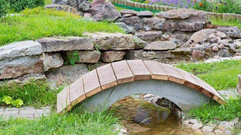 Rock garden with pond, summer bridge, and exposed culvert in a modern landscape design.