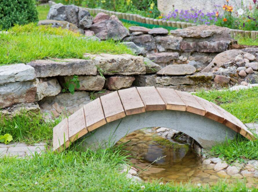 Rock garden with pond, summer bridge, and exposed culvert in a modern landscape design.