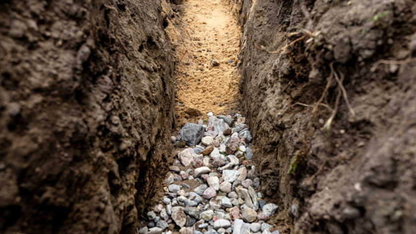 A layer of rip rap at the bottom of a yard trench to control water runoff.