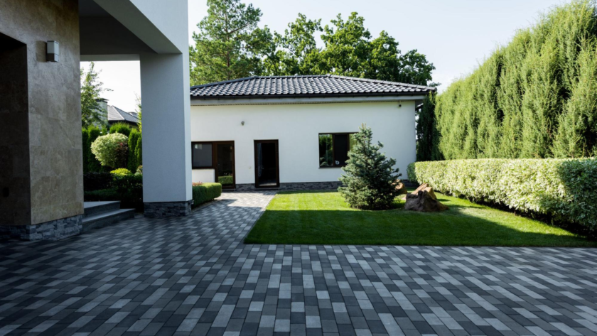 Contemporary home facade with a driveway of gray concrete pavers and a well-kept lawn