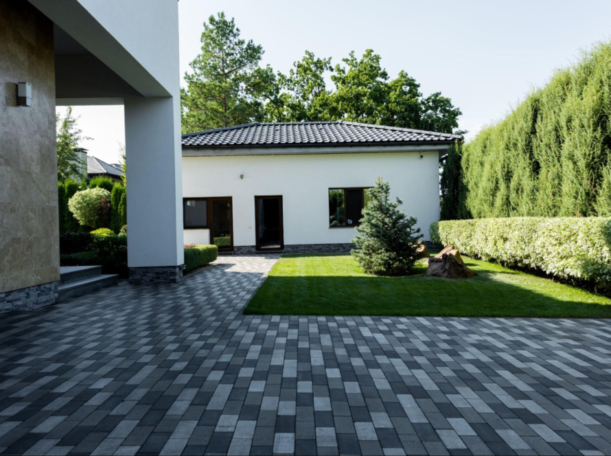 Contemporary home facade with a driveway of gray concrete pavers and a well-kept lawn